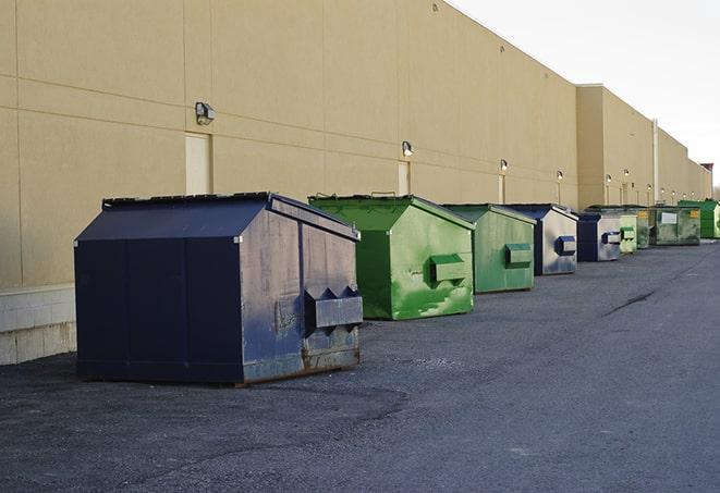 a construction worker empties a wheelbarrow of waste into the dumpster in Bowling Green, FL